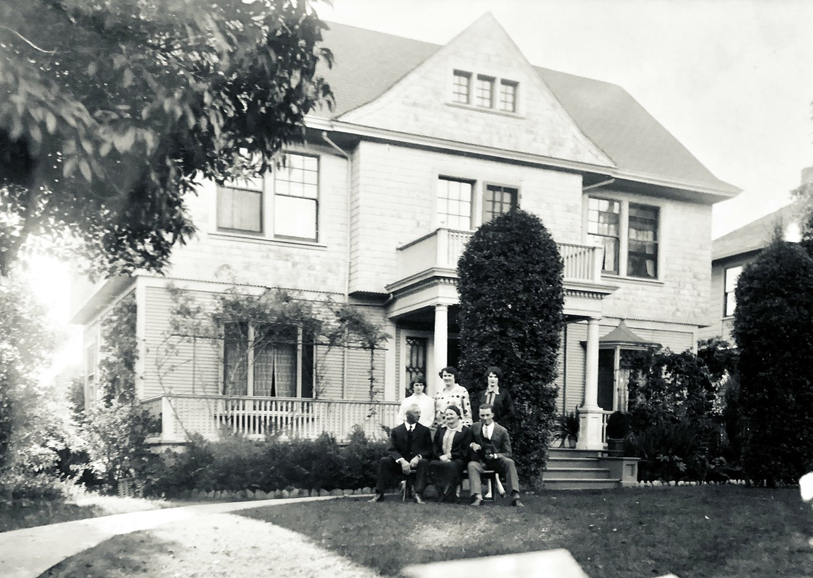 An early black-and-white photograph of the house at 1323 De La Vina Street, with the family seated on the front lawn